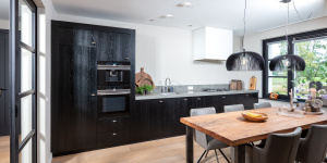 Moderne zwarte maatwerkkeuken met grijs composiet werkblad, ontworpen en gerealiseerd door Thomas Bos Interieurbouw.