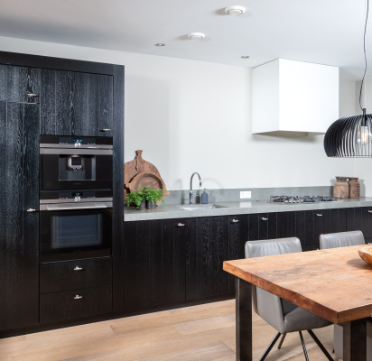 Moderne zwarte maatwerkkeuken met grijs composiet werkblad, ontworpen en gerealiseerd door Thomas Bos Interieurbouw.