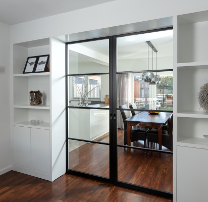 Industriële stalen ensuite-deuren met glas en ingebouwde witte kasten, op maat gemaakt door Thomas Bos Interieurbouw.