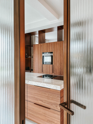 Eethoek met organische tafel in zwart eiken naast keuken in notenfineer – Thomas Bos Interieurbouw.