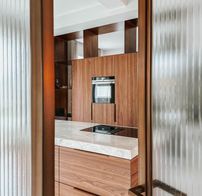 Eethoek met organische tafel in zwart eiken naast keuken in notenfineer – Thomas Bos Interieurbouw.