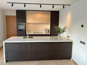 Vooraanzicht van moderne maatwerkkeuken met kookeiland, marmeren blad en minimalistische afwerking, ontworpen door Thomas Bos.