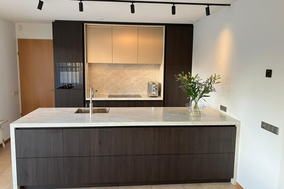 Vooraanzicht van moderne maatwerkkeuken met kookeiland, marmeren blad en minimalistische afwerking, ontworpen door Thomas Bos.